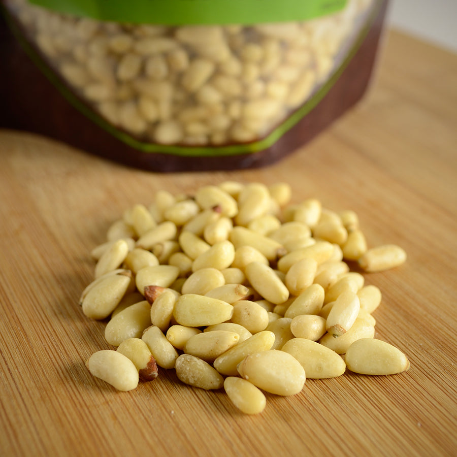 NWF1142 | pile of shelled pine nuts on a wooden cutting board with a resealable pouch in background - Thumbnail
