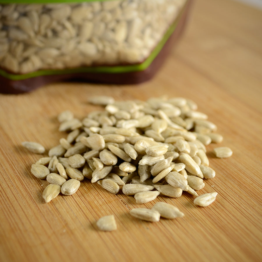 NWF1159 | hulled sunflower seeds spilled on a wooden cutting board with a resealable bag blurred in background